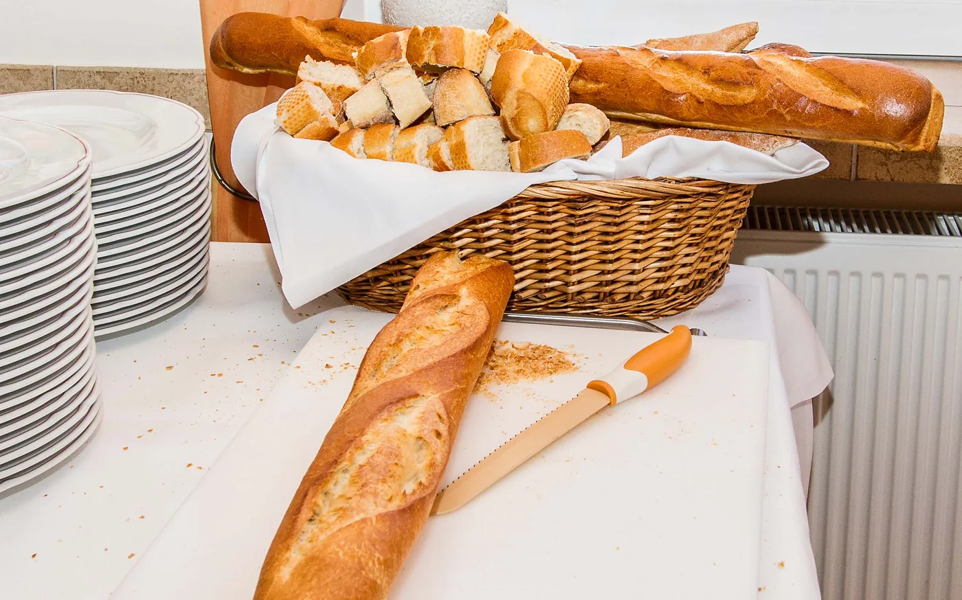 Brotkorb mit Baguette und gestapelte Teller