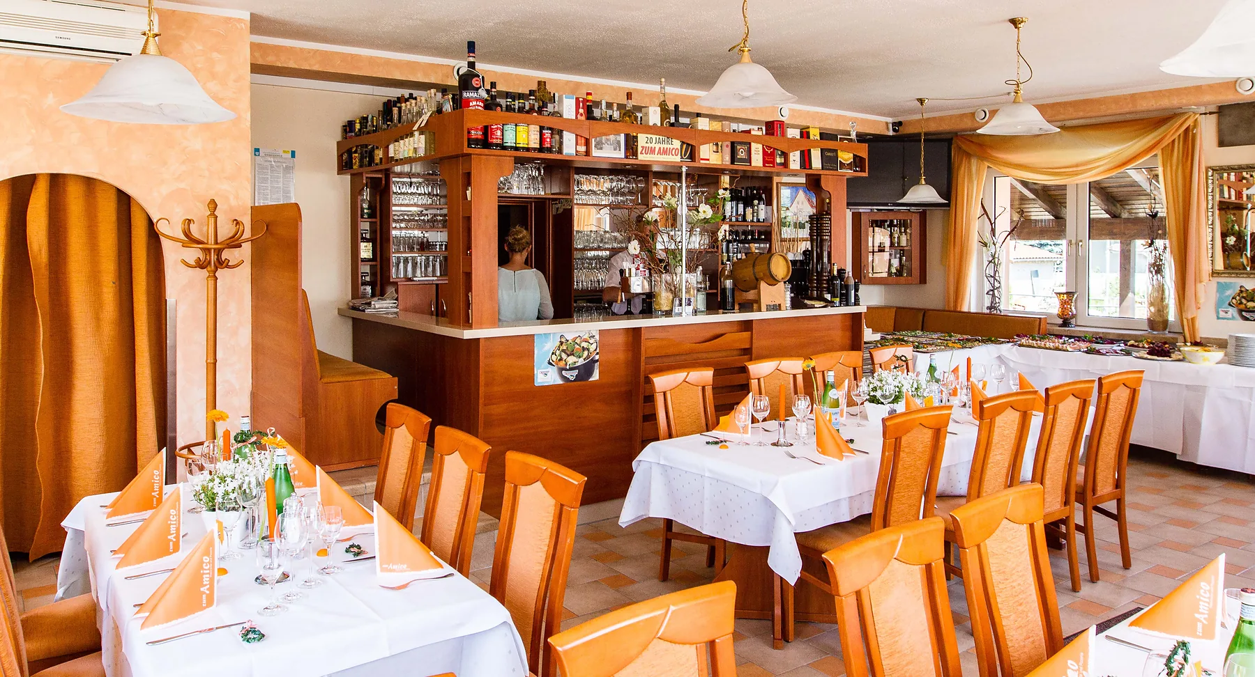 Gastraum mit eingedeckten Tischen und der Bar im Hintergrund